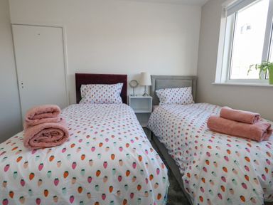 A bedroom with two single beds with fruit patterned bedding and pink towels at Lagoon View in Wyke