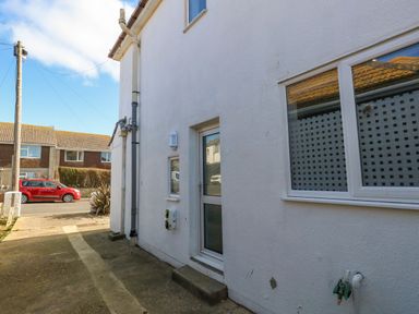 Exterior side view of a white house with a door a window and visible pipes on a sunny day at Lagoon View in Wyke