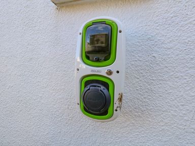 An outdoor electric vehicle charger mounted on a textured white wall at Lagoon View in Wyke