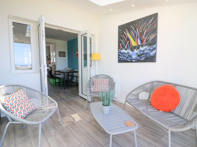 A sunroom with gray chairs and a table with a plant and cushions at Lagoon View in Wyke
