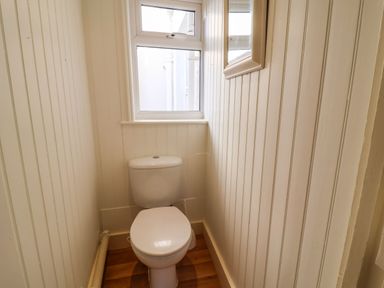 A small bathroom with a toilet and a window above at Tuckaway Cottage in Aldeburgh