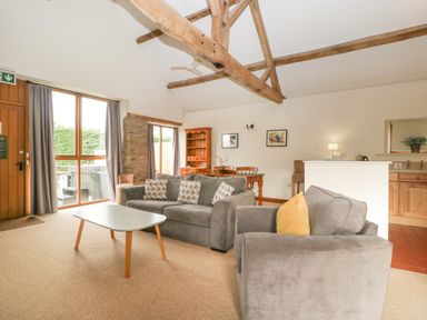A living room with sofas coffee table dining table and kitchen area at Peartree Cottage in Stanford Bishop near Bromyard