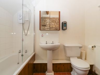 A bathroom with a bathtub and shower, a sink with a mirror cabinet above, and a toilet at Peartree Cottage Stanford Bishop near Bromyard