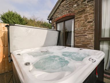 An outdoor hot tub with bubbling water next to a stone wall house at Peartree Cottage Stanford Bishop near Bromyard