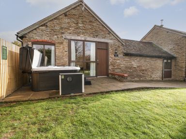 Stone cottage exterior with patio door hot tub and lawn at Peartree Cottage in Stanford Bishop near Bromyard