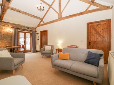 A living room with gray sofas wooden doors and exposed wooden beams at Clover Patch Cottage in Stanford Bishop near Bromyard