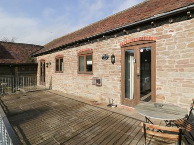 Stone wall cottage exterior with windows doors and wooden table with chairs on patio at Clover Patch Cottage Stanford Bishop near Bromyard