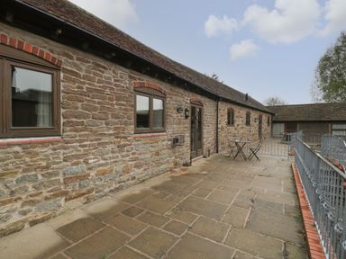 A stone patio with a metal table and chairs outside a stone building at Clover Patch Cottage Stanford Bishop near Bromyard