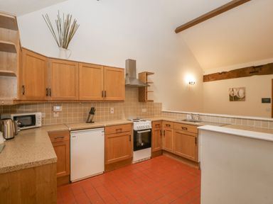 A kitchen with wooden cabinets tiled backsplash and red tiled floor at Honeysuckle Cottage Stanford Bishop near Bromyard