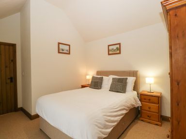 A bedroom with a double bed lamps on bedside tables and framed pictures on walls at Honeysuckle Cottage Stanford Bishop near Bromyard