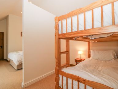 A bedroom with wooden bunk beds and a bedside table lamp at Honeysuckle Cottage in Stanford Bishop near Bromyard