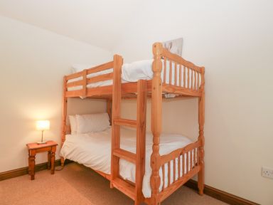 A bedroom with a wooden bunk bed and a small side table with a lamp at Honeysuckle Cottage Stanford Bishop near Bromyard
