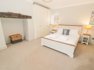 A bedroom with a double bed two bedside tables with lamps a wardrobe and a wicker basket at Lakeside Cottage in Llanrug