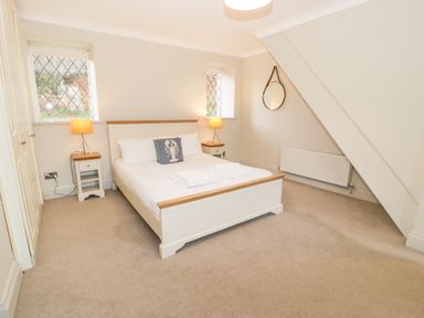 A bedroom with a double bed bedside tables and lamps under two windows at Lakeside Cottage in Llanrug