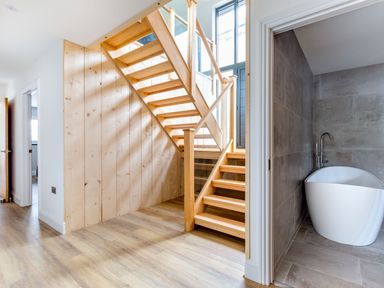 A staircase made of wood next to a bathroom with a white freestanding bathtub at Breakers View in Polzeath