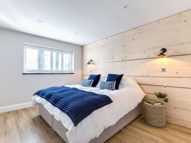 A bedroom with a double bed and nightstand with a plant and book at Breakers View in Polzeath