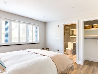 A bedroom with a bed a bathroom with a toilet and an open closet at Breakers View in Polzeath