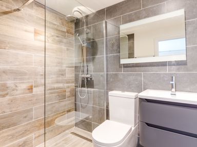 A bathroom with a shower area toilet sink and mirror at Breakers View in Polzeath