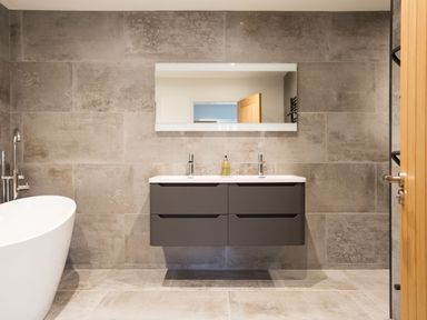 A bathroom with a double sink vanity mirror and freestanding bathtub at Breakers View in Polzeath