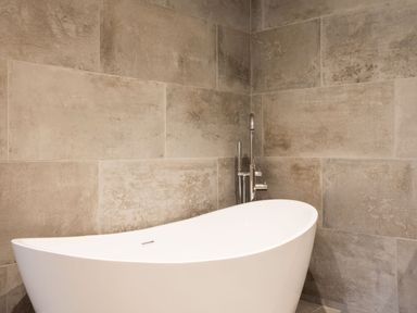 A white freestanding bathtub with a chrome faucet against a tiled wall at Breakers View in Polzeath
