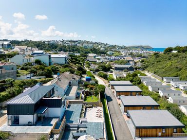 A coastal residential area with houses roads and a parking lot near the sea at Breakers View in Polzeath