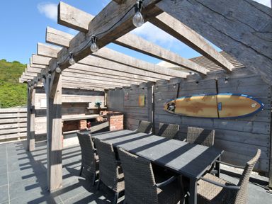 An outdoor dining area with a table and chairs under a pergola at Breakers View in Polzeath