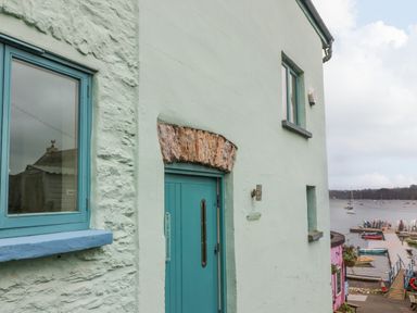 A light green building with blue windows and door near a harbor with boats at 1 The Old Brewhouse in Dartmouth