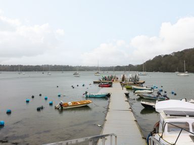 A dock with small boats and sailboats on the water at 1 The Old Brewhouse in Dartmouth
