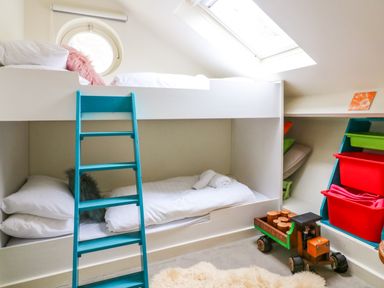 A small bedroom with bunk beds a turquoise ladder a toy truck and storage bins at 1 The Old Brewhouse in Dartmouth