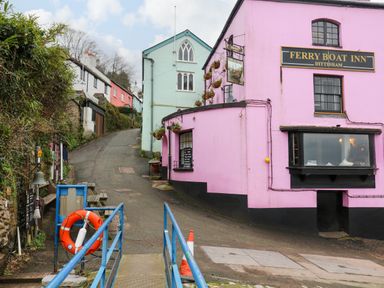 A street with colorful houses and a pink building labeled ferry boat inn in Dittisham