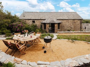 An outdoor dining area with a table and chairs at Hoppers Barn in Pancrasweek near Holsworthy
