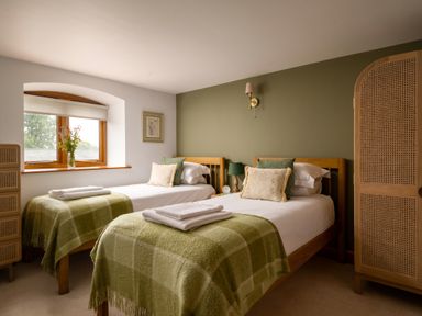 A bedroom with twin beds and a window at Hoppers Barn Pancrasweek near Holsworthy