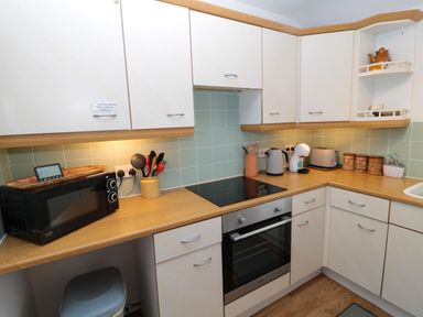 A kitchen with wooden countertops white cabinets a microwave oven an electric stove a kettle a toaster and utensils at 60B Castlegate in Berwick-Upon-Tweed