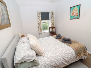 A bedroom with a bed pillows a chair window with curtains and paintings on the walls at 60B Castlegate in Berwick-Upon-Tweed