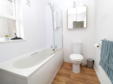A bathroom with a bathtub a shower a toilet a towel on a rack and a window at 60B Castlegate in Berwick-Upon-Tweed