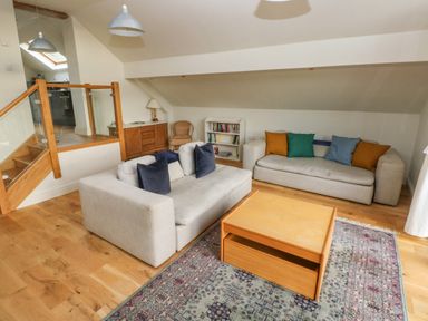 A living room with two sofas a wooden coffee table bookshelf and stairs at Green Grove Barn in Peniel near Carmarthen