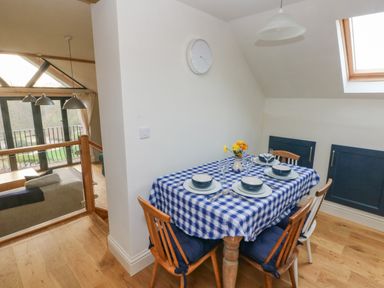 A dining area with a table set for four with blue and white checkered tablecloth near a skylight window at Green Grove Barn in Peniel near Carmarthen