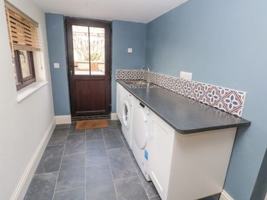 A laundry room with a washing machine dryer sink and door at Green Grove Barn in Peniel near Carmarthen
