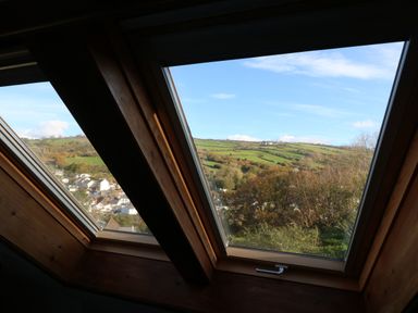 A view of houses and green hills through a skylight window at Hillsview in Combe Martin