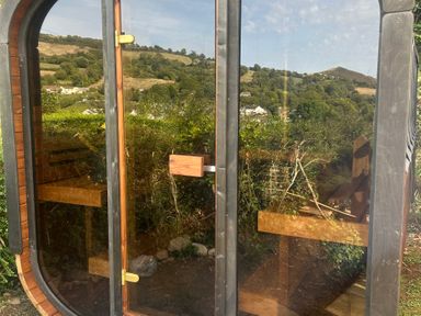 A structure with a glass door and benches at Hillsview in Combe Martin