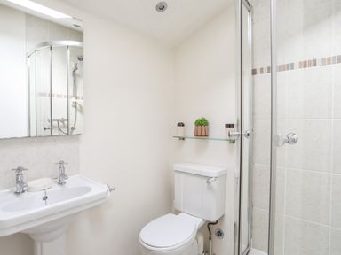 A bathroom with a pedestal sink a toilet and a glass shower enclosure at Tir Eironwy in Dinas near Nefyn