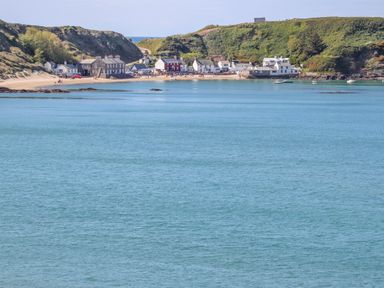 A coastal village with houses near a sandy beach and hills in the background at Tir Eironwy Dinas near Nefyn