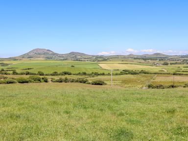 A grassy field with rolling hills and clear sky at Tir Eironwy in Dinas near Nefyn