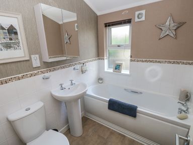 A bathroom with a toilet sink bathtub a window and wall decorations at 1 Hornbeam Lodge in Narberth