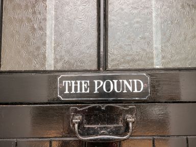 A close up of a black door with a handle and a sign that says The Pound at The Pound in Porlock