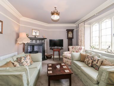 A living room with two light green sofas floral armchair wooden coffee table television and a fireplace at The Pound in Porlock