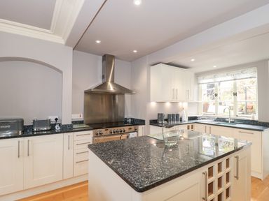 A kitchen with a central island, stovetop with stainless steel hood, countertop appliances, and a window at The Pound in Porlock