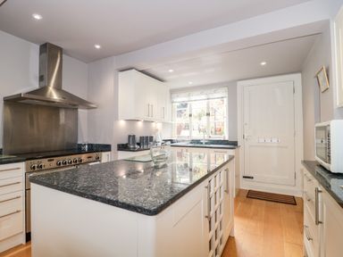A kitchen with a large island counter chimney stove window and wooden floor at The Pound in Porlock