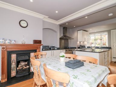 A kitchen and dining area with a wooden table and chairs a fireplace and white cabinets at The Pound in Porlock