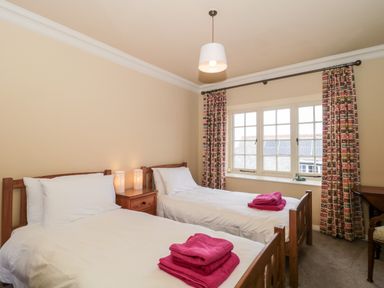 A bedroom with two single beds and pink towels at The Pound in Porlock